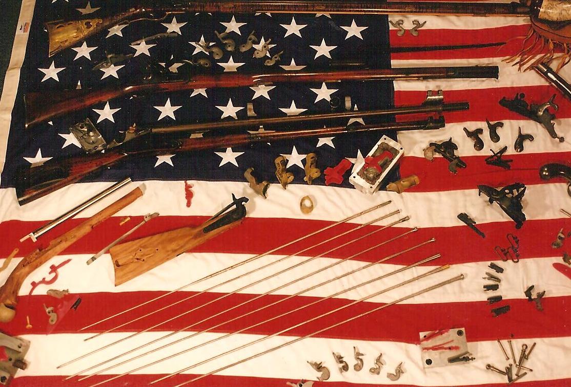 Castings, ramrods and flintlock rifles laid out on an American flag